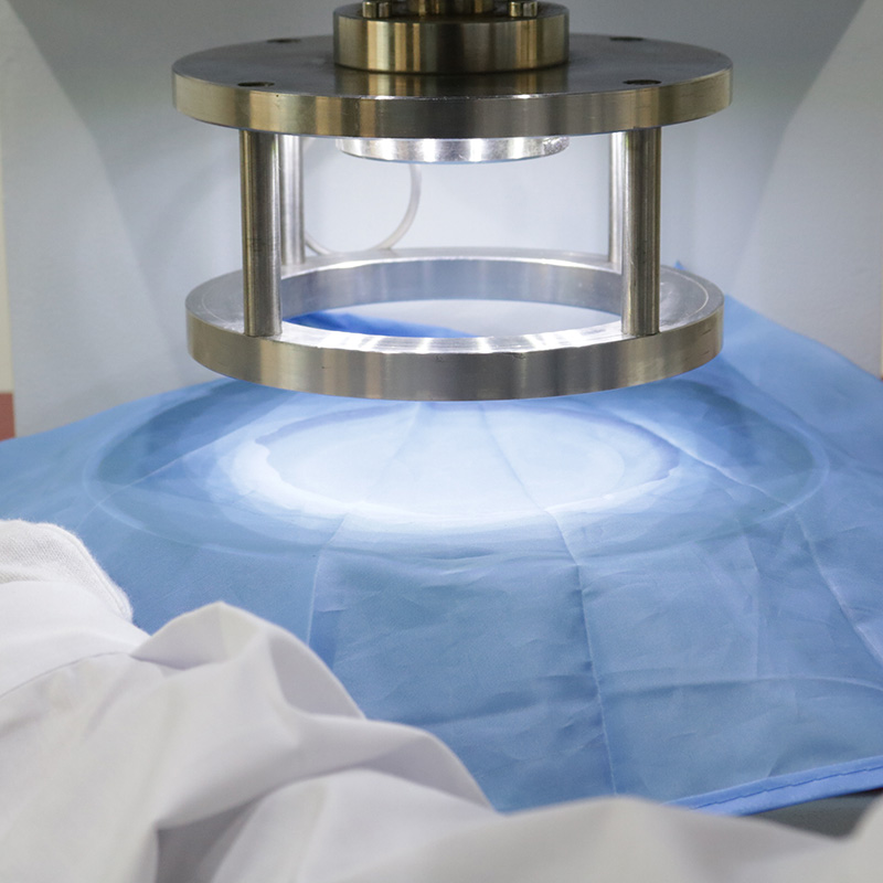 Blue fabric clamped in a hydrostatic pressure test fixture, showing the water-resistance test without visible branding.
