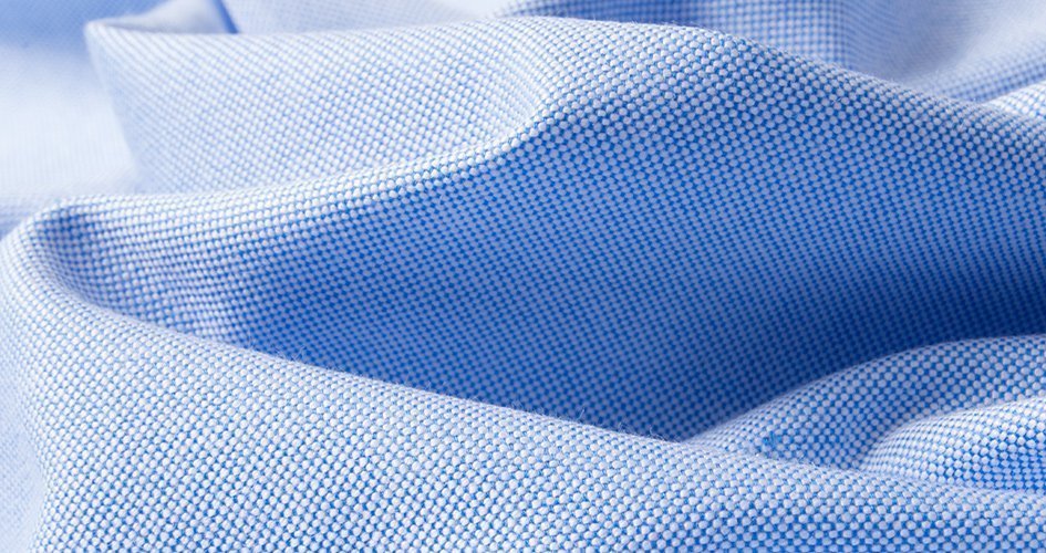 Light blue Oxford cloth close-up showing the traditional basket-weave texture.