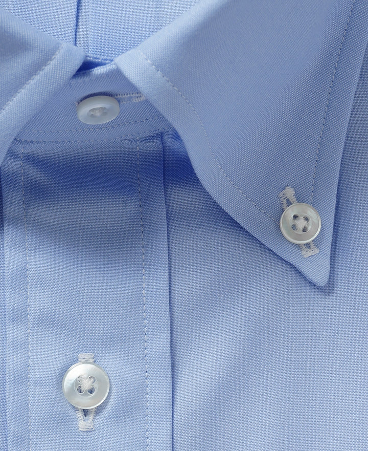 Close-up of a light blue pinpoint Oxford shirt showing its finer surface grain around the collar and placket.