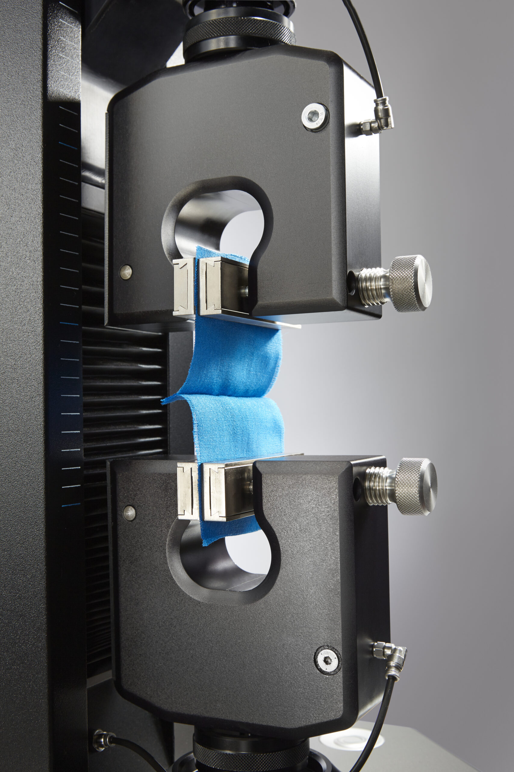Fabric specimen clamped in a tensile tester for seam slippage testing
