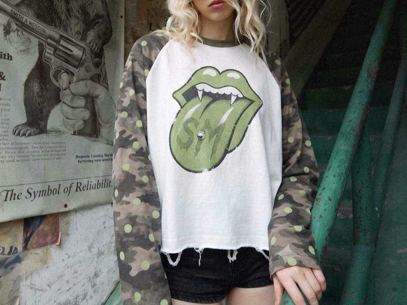 Model wearing a white graphic raglan top with camouflage sleeves