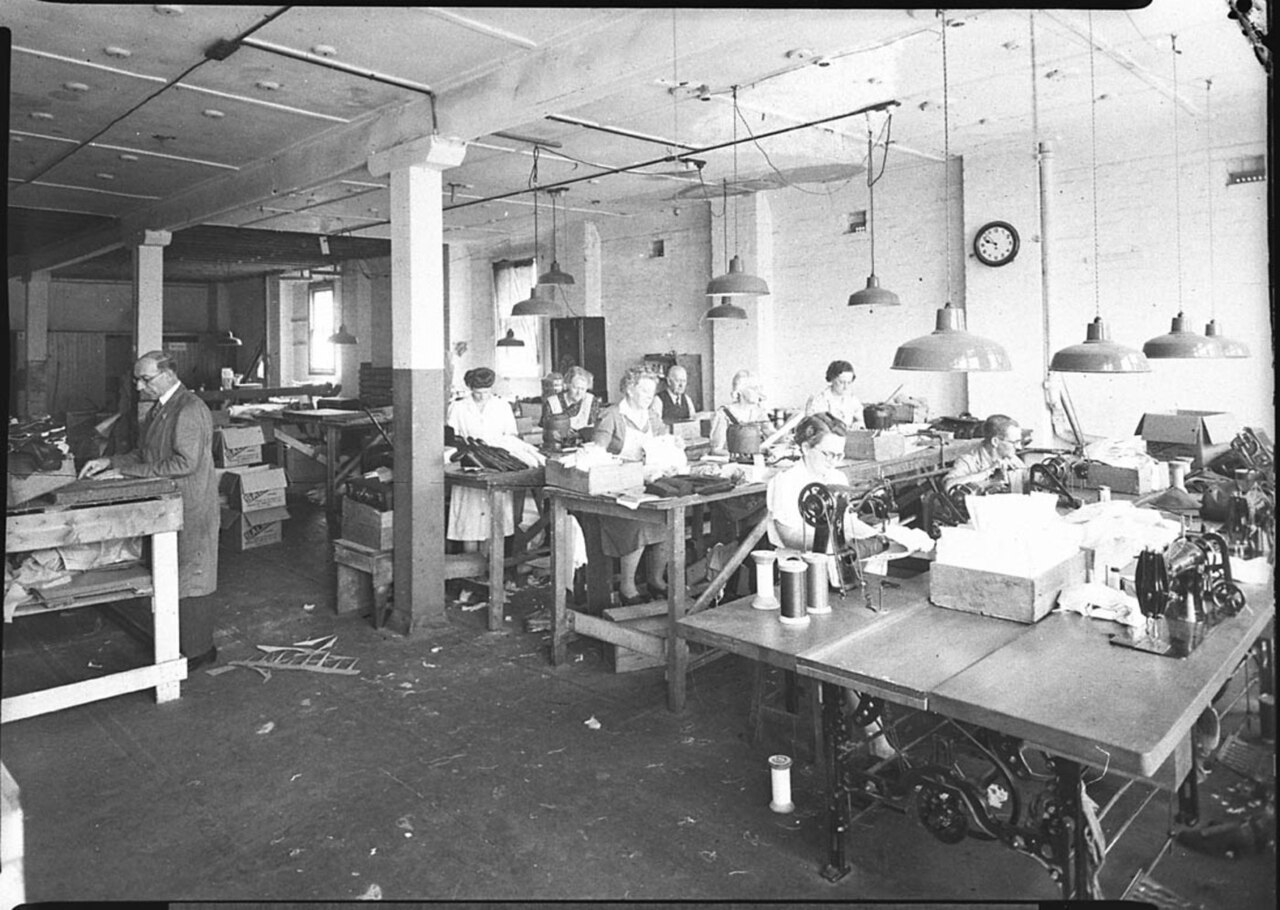 A clothing workshop with workers at sewing machines and work tables arranged across the production floor