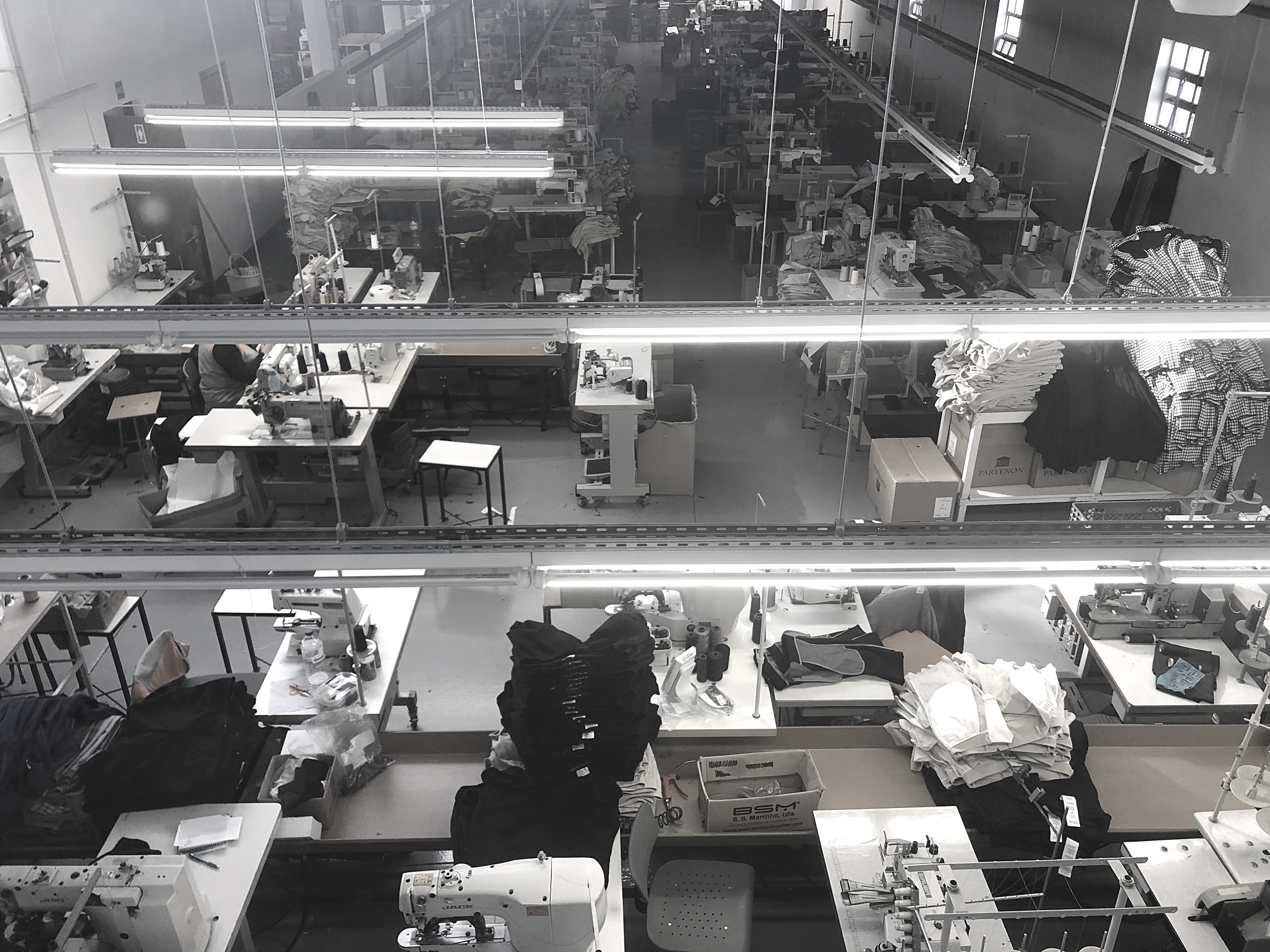 An elevated view across a garment factory floor in Portugal, with sewing machines, worktables and stacks of cut and assembled clothing