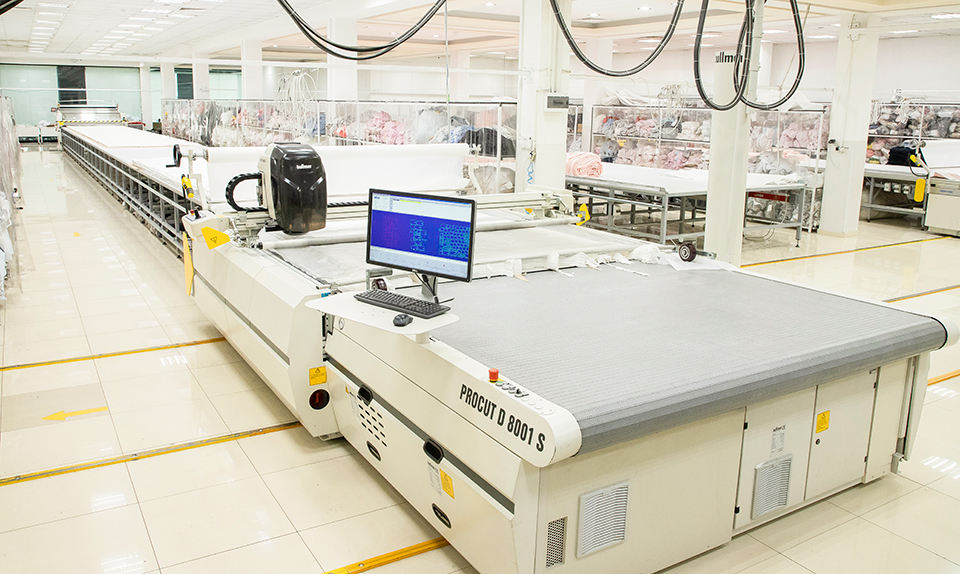 Automatic garment fabric cutting table with digital marker control screen.