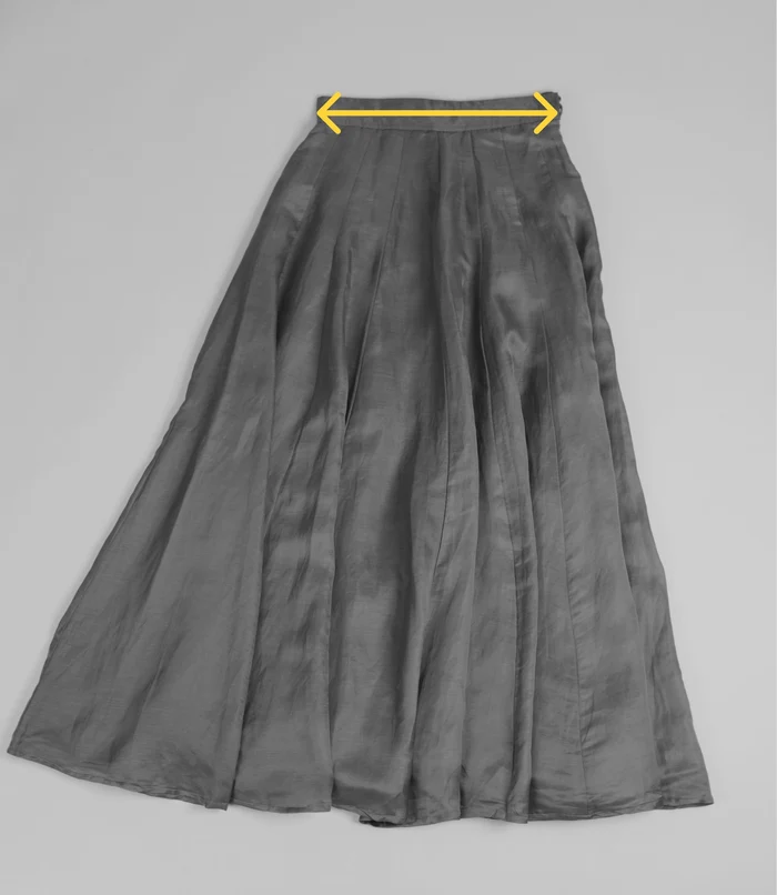 Black skirt laid flat with a measurement marker across the waistband