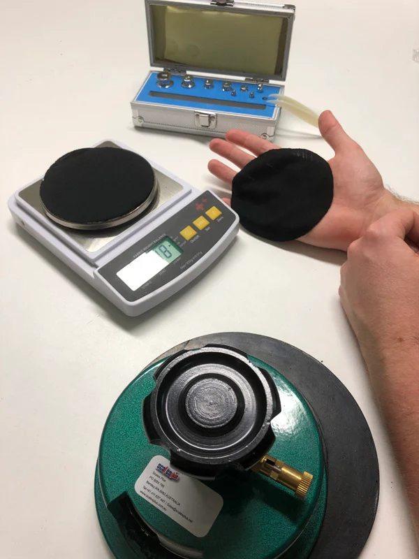 Circular fabric swatches being weighed on a digital scale during a fabric GSM test.