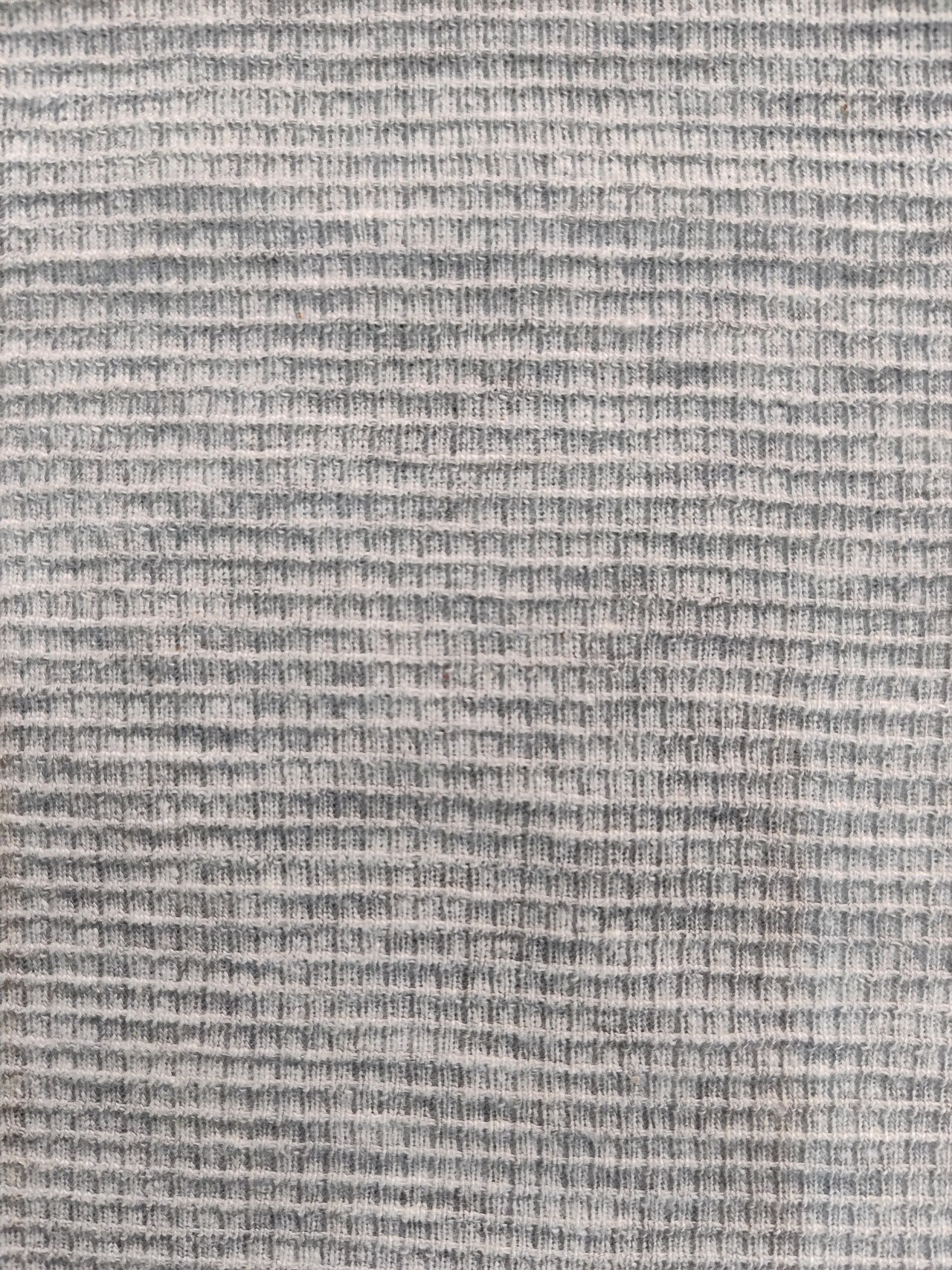 Close-up of knitted waffle fabric showing raised ribs and recessed cells.
