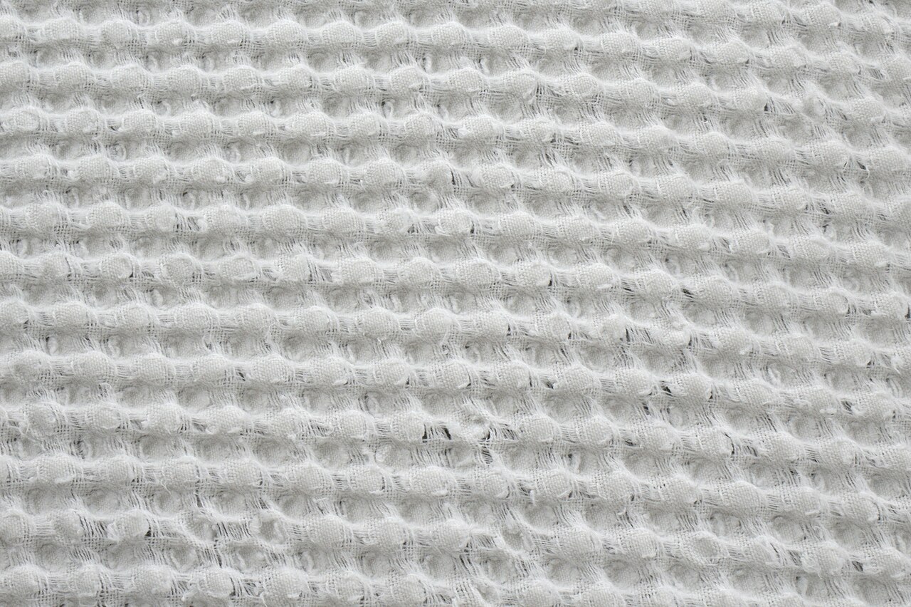 Close-up of woven white waffle fabric made with warp and weft yarns.
