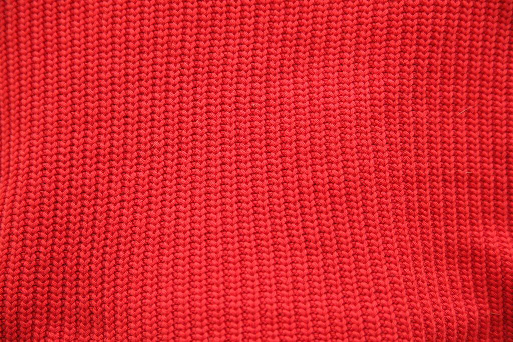 Close view of red rib knit showing raised stitch columns and recessed channels.