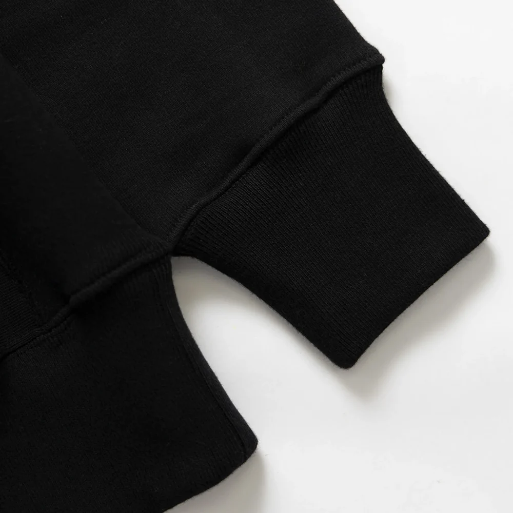 Close view of the ribbed cuff and waistband on a black sweatshirt.