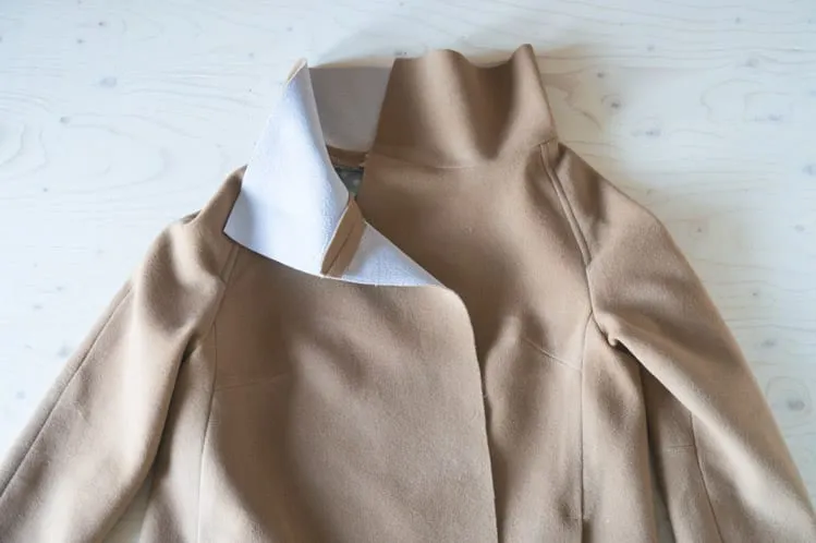 Coat construction reference: an unfinished camel-colored coat with its collar attached and interfacing visible