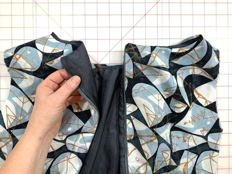 Construction reference: a concealed zipper between printed dress panels with the dark bodice lining lifted to show the attachment
