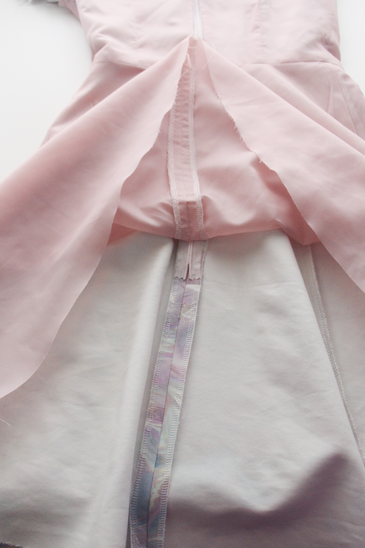 Construction reference: inside a partially assembled dress, showing pink bodice lining and a center-back zipper on the white shell