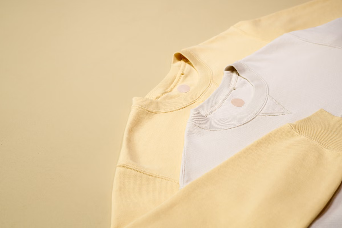 Cream and pale yellow crewneck sweatshirts with ribbed necklines.