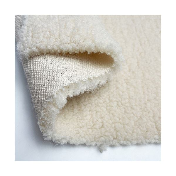 Cream bonded sherpa fabric folded back to show the curly pile and the woven backing underneath.