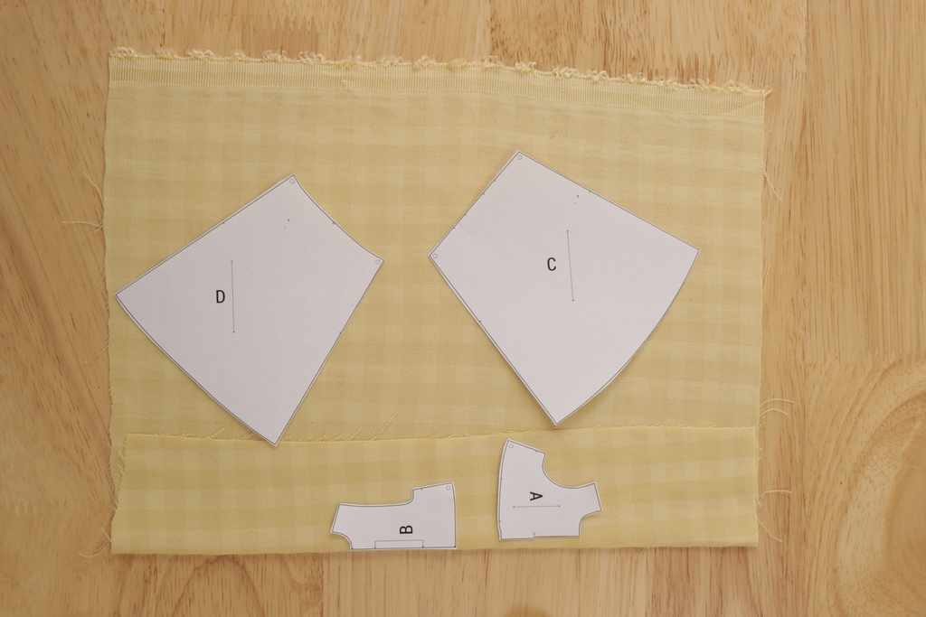 Cutting reference: paper dress pattern pieces positioned diagonally on checked fabric for a bias cutting layout