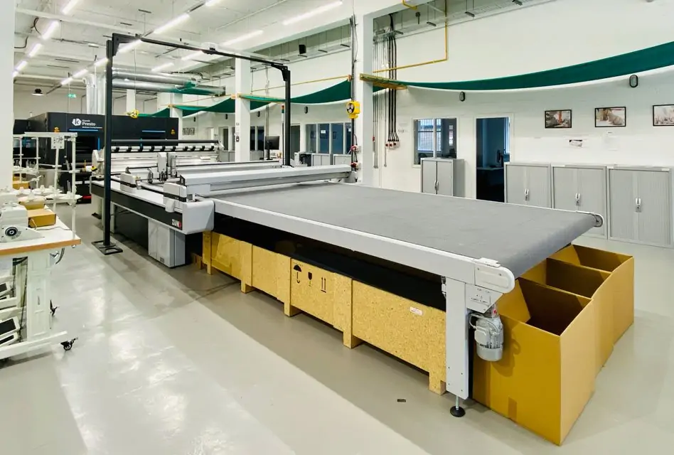 Digital fabric cutting table in a garment micro-factory with no operator in frame.