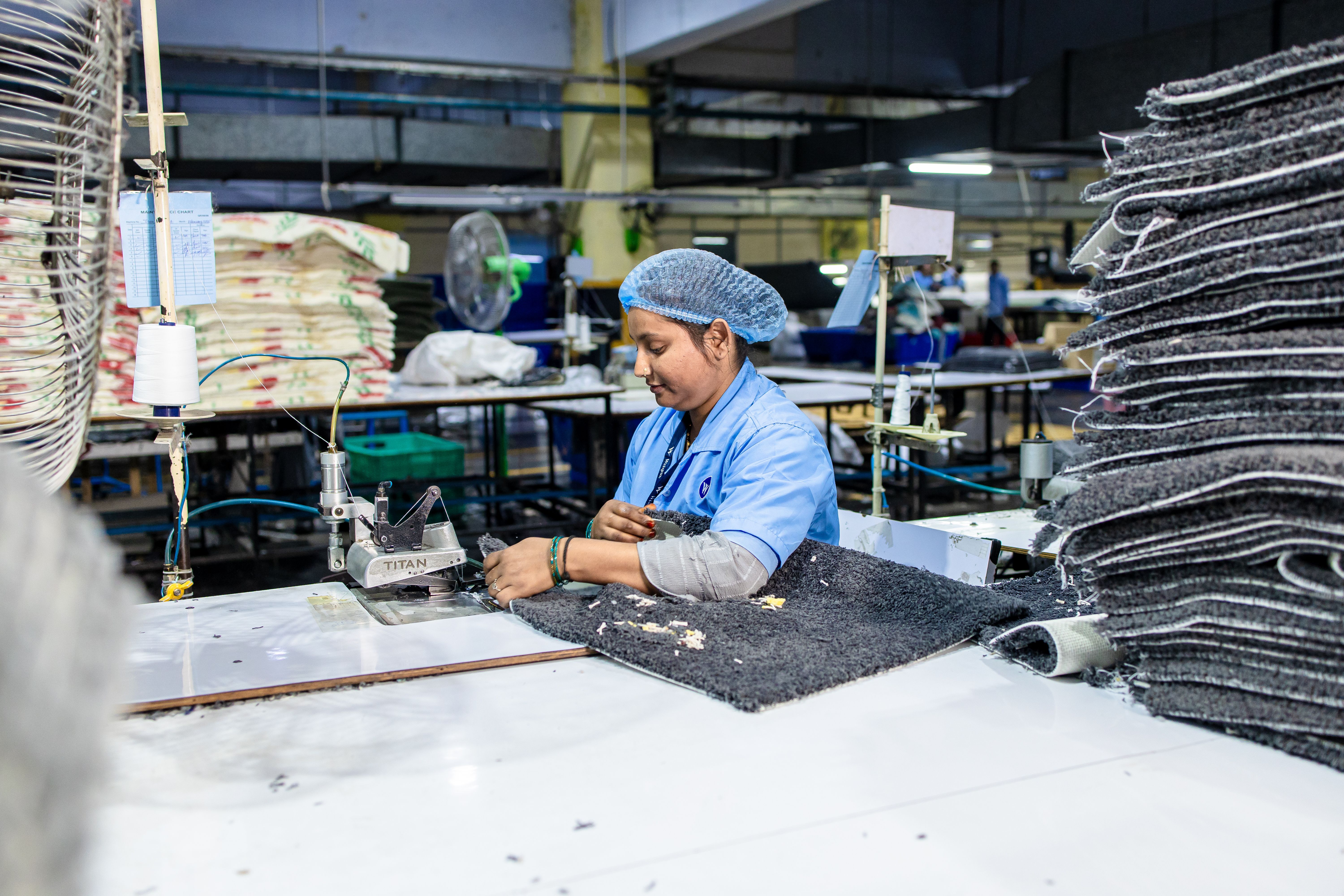 Factory worker sewing garment fabric on an industrial machine
