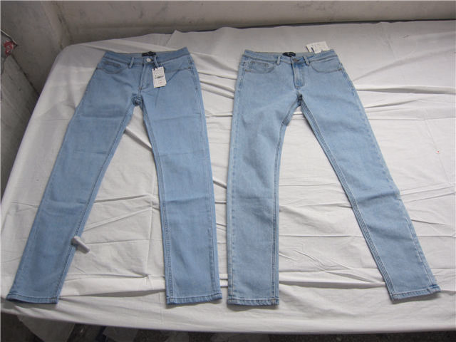 Finished jeans laid flat with inspection tags for production approval and quality checking