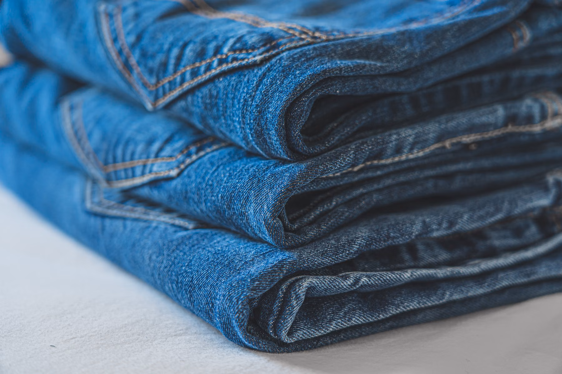 Folded blue denim jeans showing wash, stitching and finished garment construction