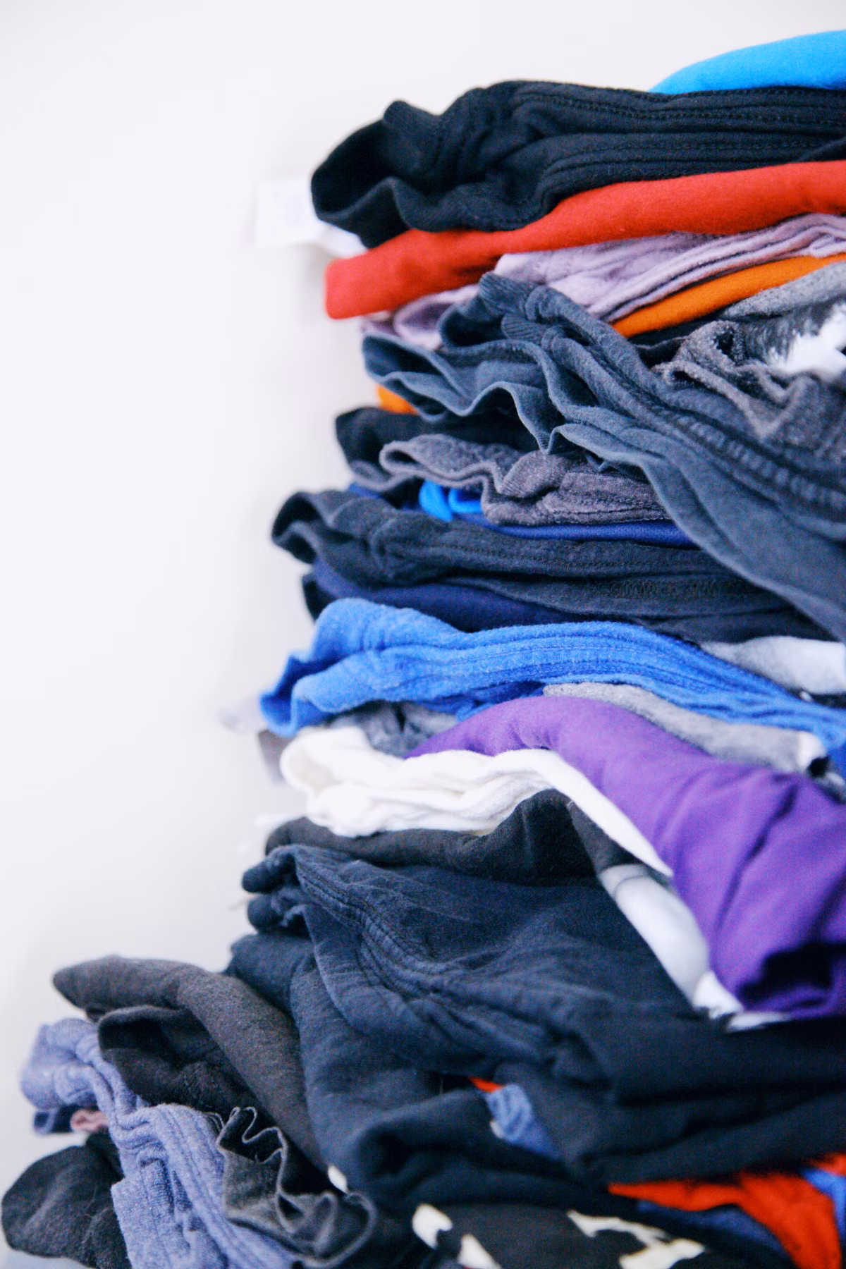 Folded garments stacked in blue, gray, red and purple.