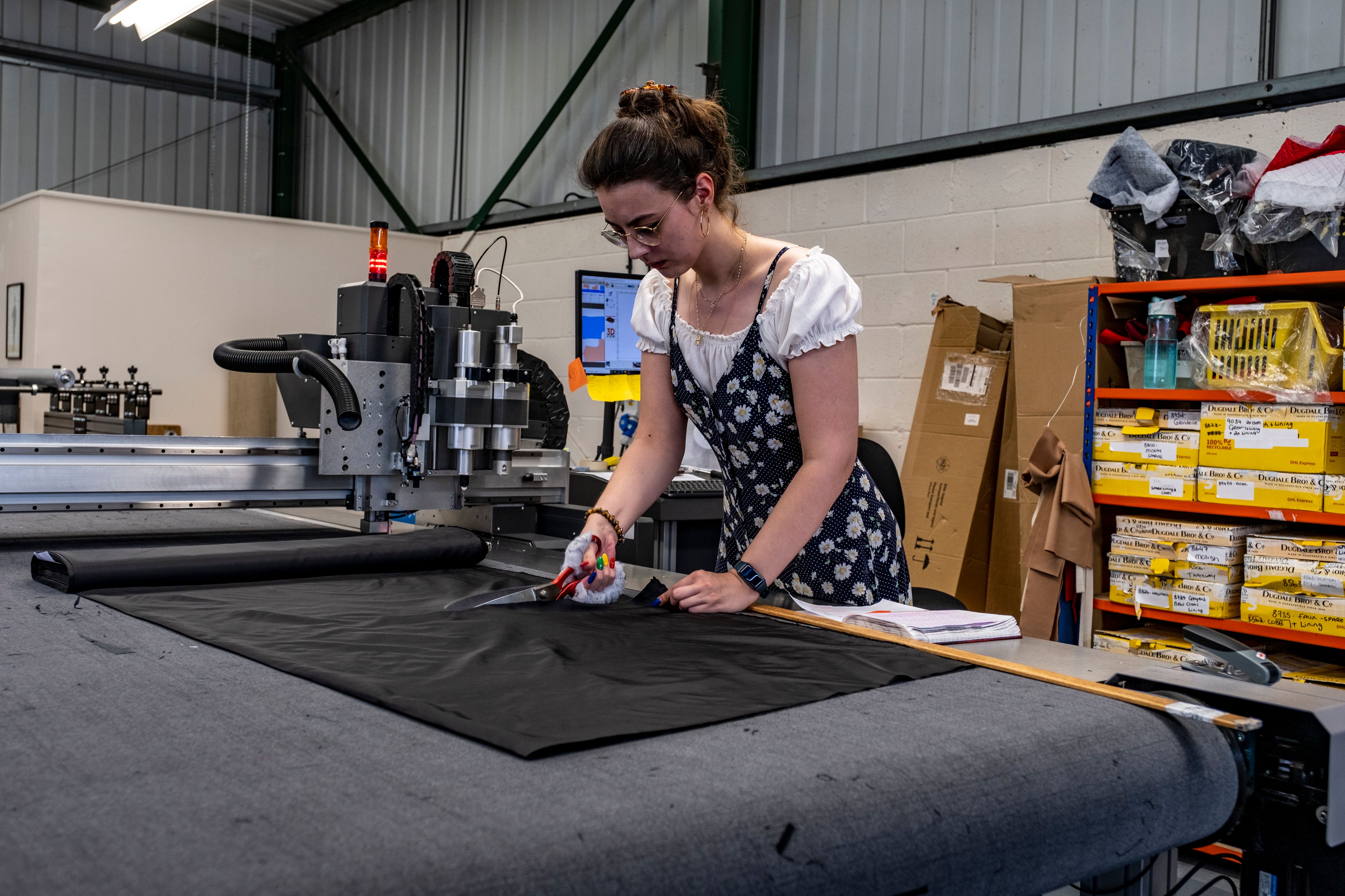 Garment worker cutting fabric on a production cutting table