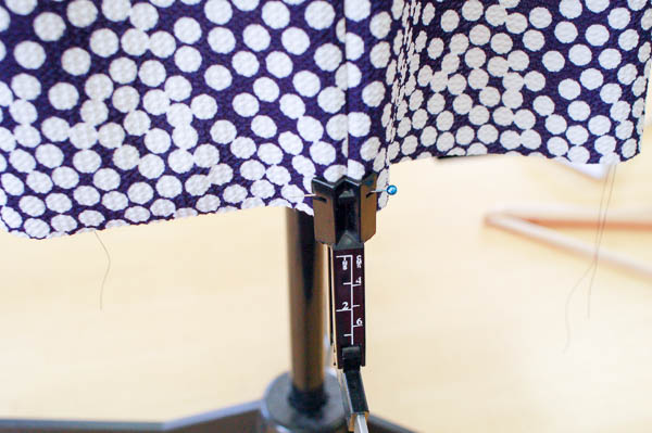 Hem-level reference: a height gauge placed at the hem of a printed dress to establish an even lower edge.