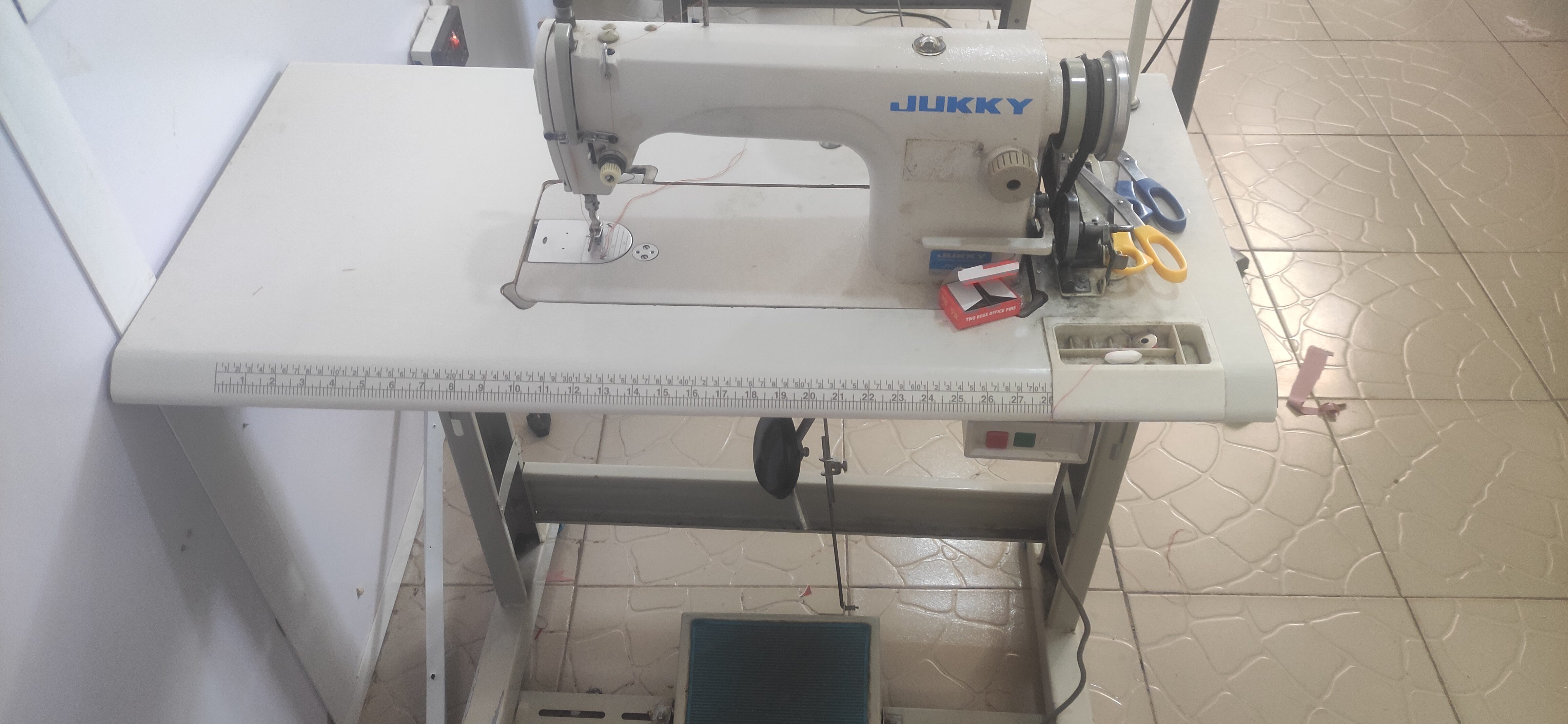 Industrial sewing machine on a worktable used for garment production.