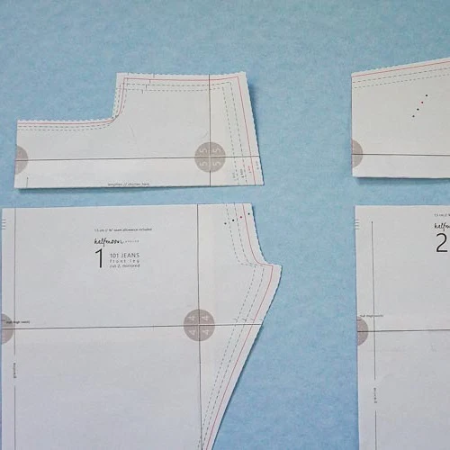 Jeans paper pattern pieces showing multiple graded size lines and rise adjustment references