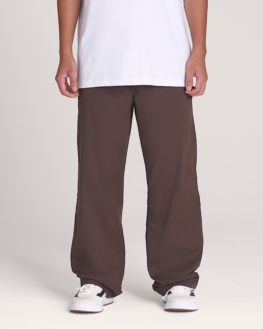 Loose brown chinos worn with a long white T-shirt and white low-top skate shoes