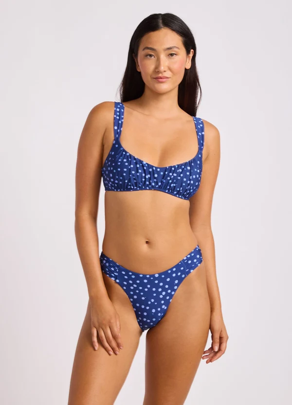 Navy polka-dot bikini top with shoulder straps and a soft bralette shape
