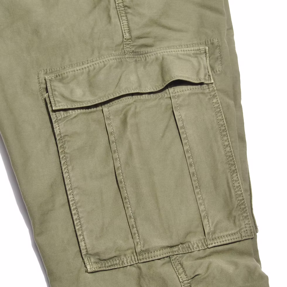 Olive cargo pocket close-up showing the flap, expansion pleat and topstitching