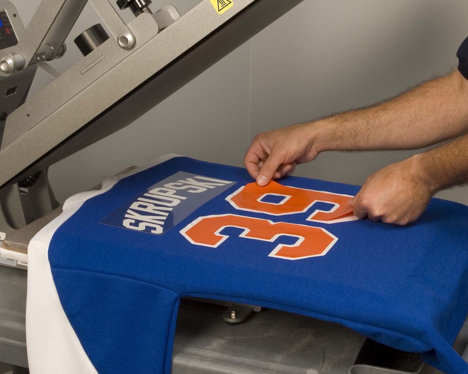 Player number being positioned on a jersey during heat application