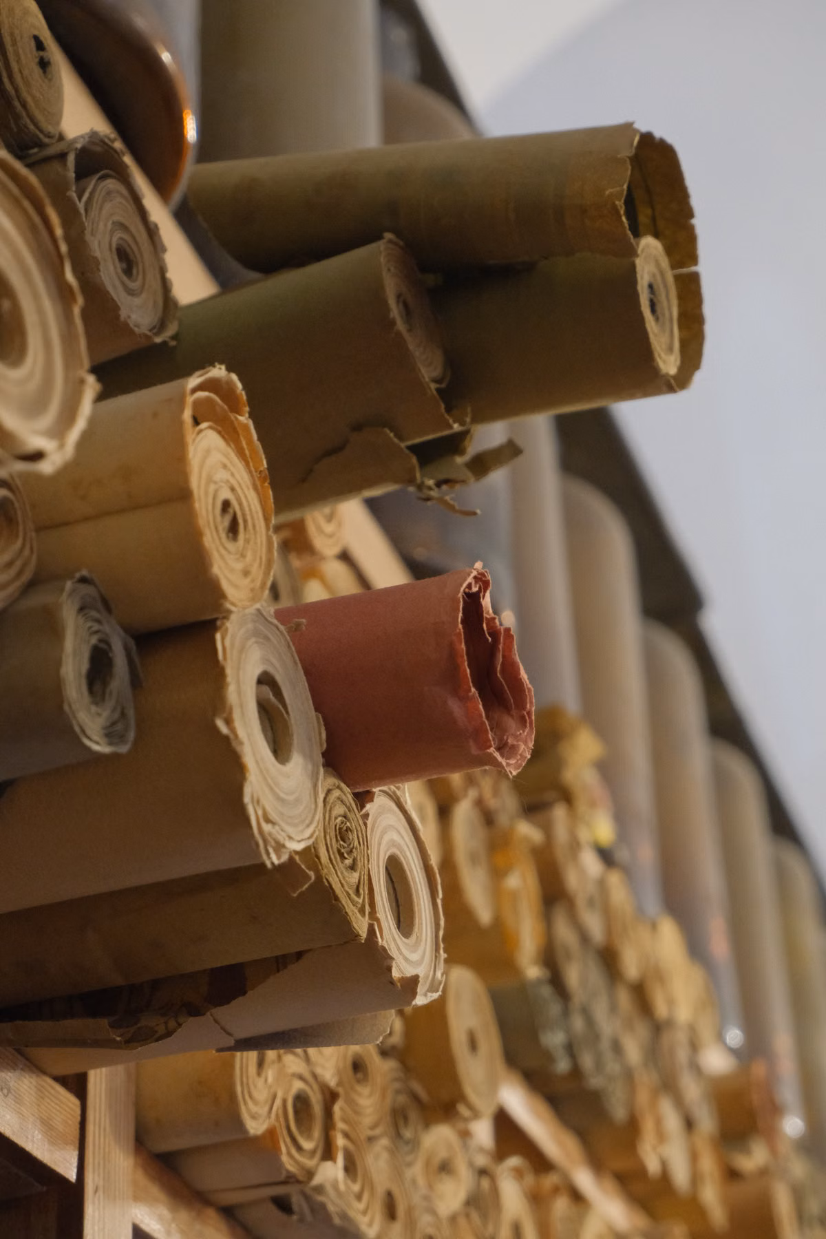 Rows of beige, olive and brown fabric rolls on shelving.
