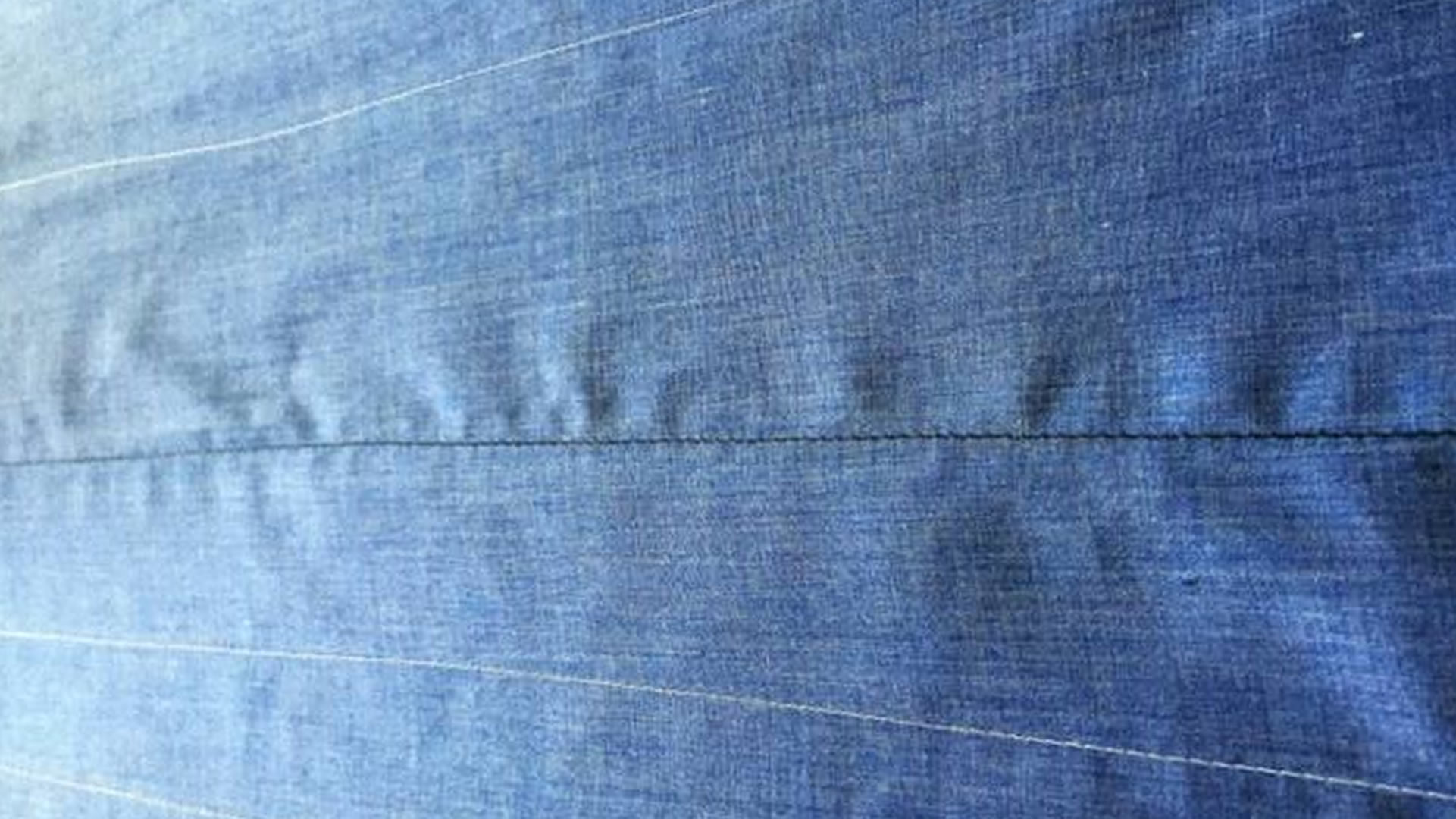 Seam-defect reference: visible puckering and ripples along a sewn line in blue fabric.