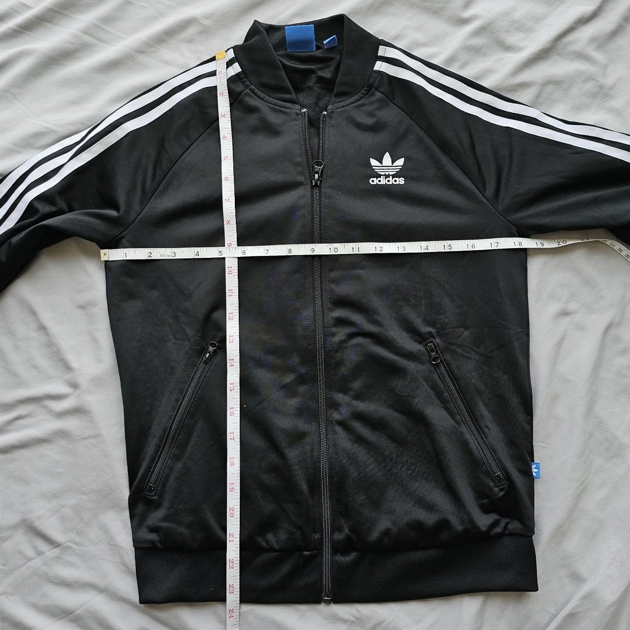 Track jacket laid flat with chest and length measurements