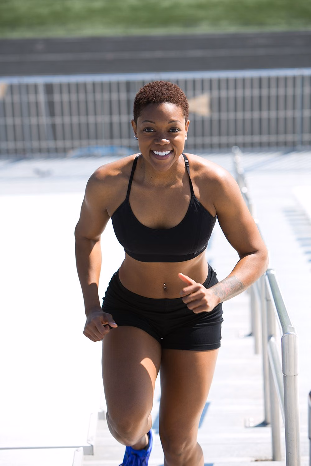 Woman in black sports bra and running shorts smiling outdoors