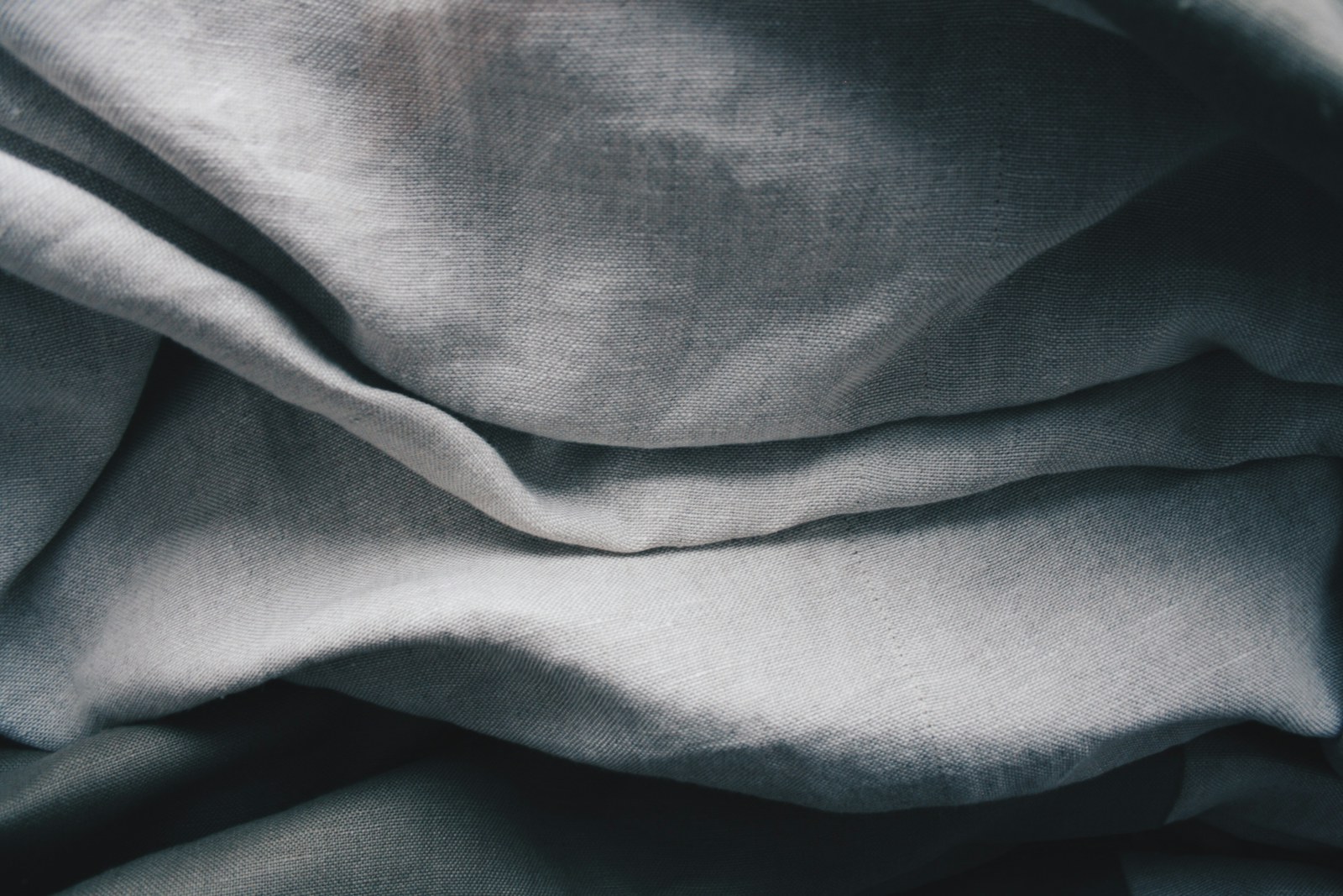Grey textile falling into folds to show how fabric drape changes visible garment volume